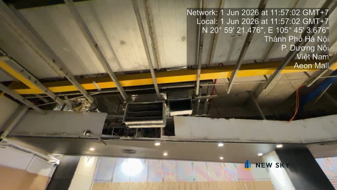 Nhìn ngược lên trần một mặt bằng ở Aeon Mall Hà Đông: hai hộp gió thò xuống qua lỗ chờ trên trần thạch cao, phía trên là khung trần thép và sàn bê tông, phía dưới là dải mặt tiền đã lắp đèn.