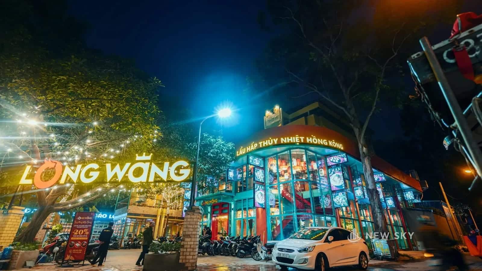 Mặt tiền nhà hàng Long Wang 84 Ngọc Khánh buổi tối, biển hiệu sáng đèn, mặt kính hai tầng treo đèn lồng.