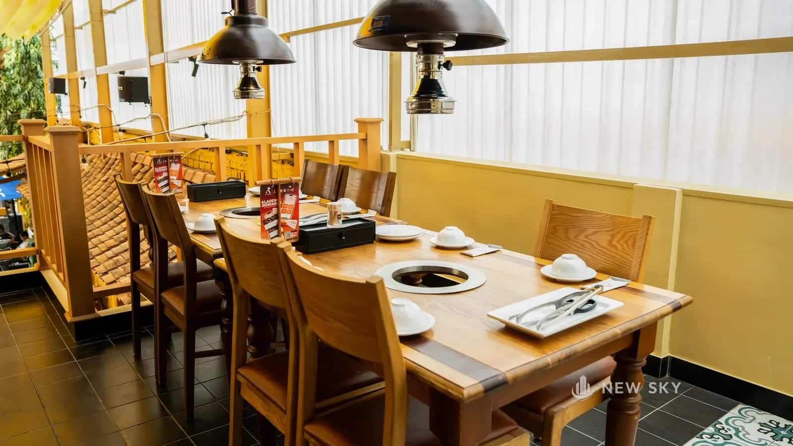Phòng ăn Khèn Nướng số 9 Thoại Ngọc Hậu sau khi hoàn thiện, tường vàng và cửa sổ tròn lấy sáng.