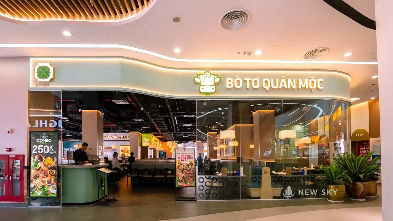 Gian nhà hàng Bò Tơ Quán Mộc trong trung tâm thương mại Vincom Mega Mall Royal Island: dải biển chữ nổi cong theo mặt dựng, gian mở thẳng ra lối đi chung.