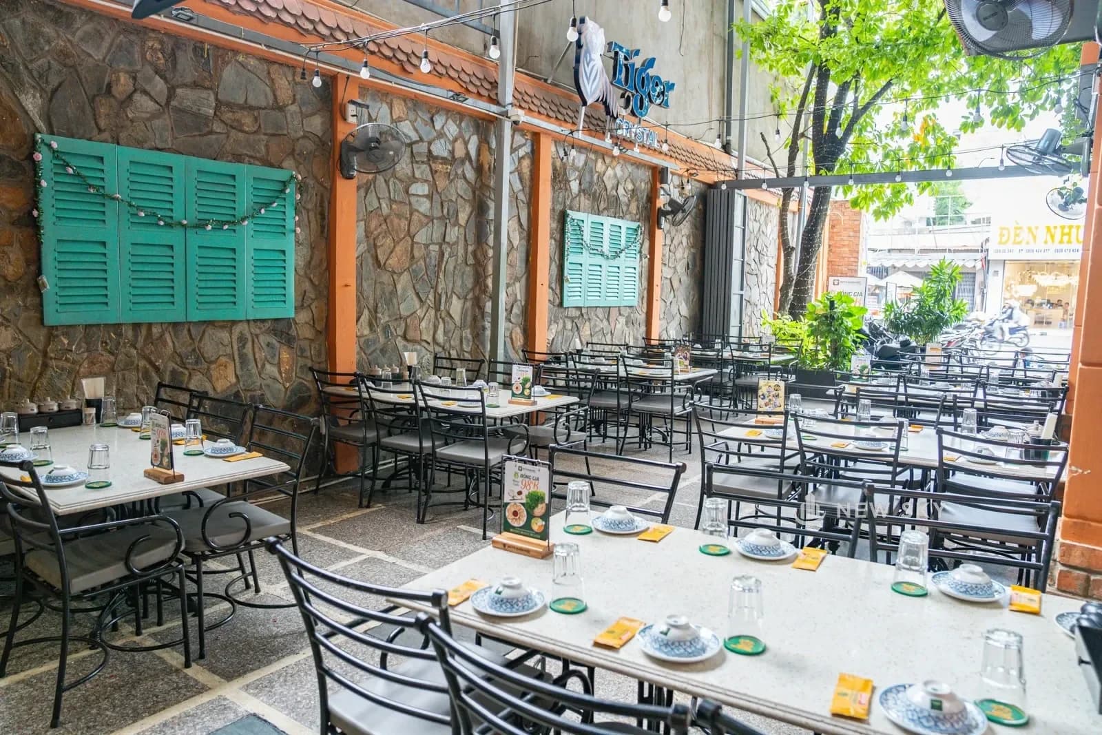 Mặt tiền Bò Tơ Quán Mộc 111 Gò Dầu: nhà hai tầng bo vòm cuốn, dây leo rủ kín ban công, biển chữ vàng gác trên khung sắt chạy suốt bề ngang.