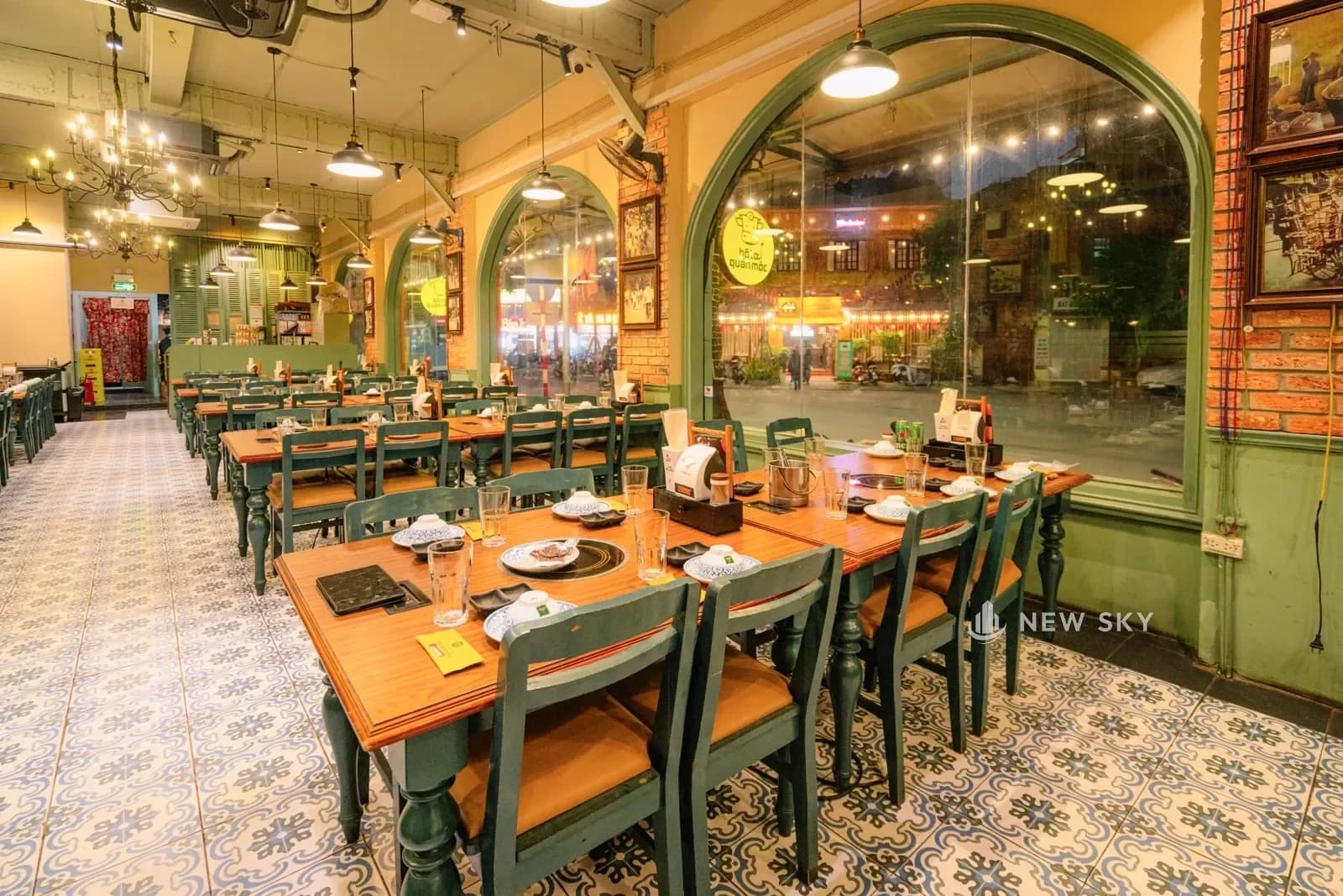Mặt tiền Bò Tơ Quán Mộc 1 Tăng Bạt Hổ về đêm: biển chữ đèn đặt ở chỗ bo góc nhà, dải biển và đèn dây chạy dọc mặt phố bên cạnh.