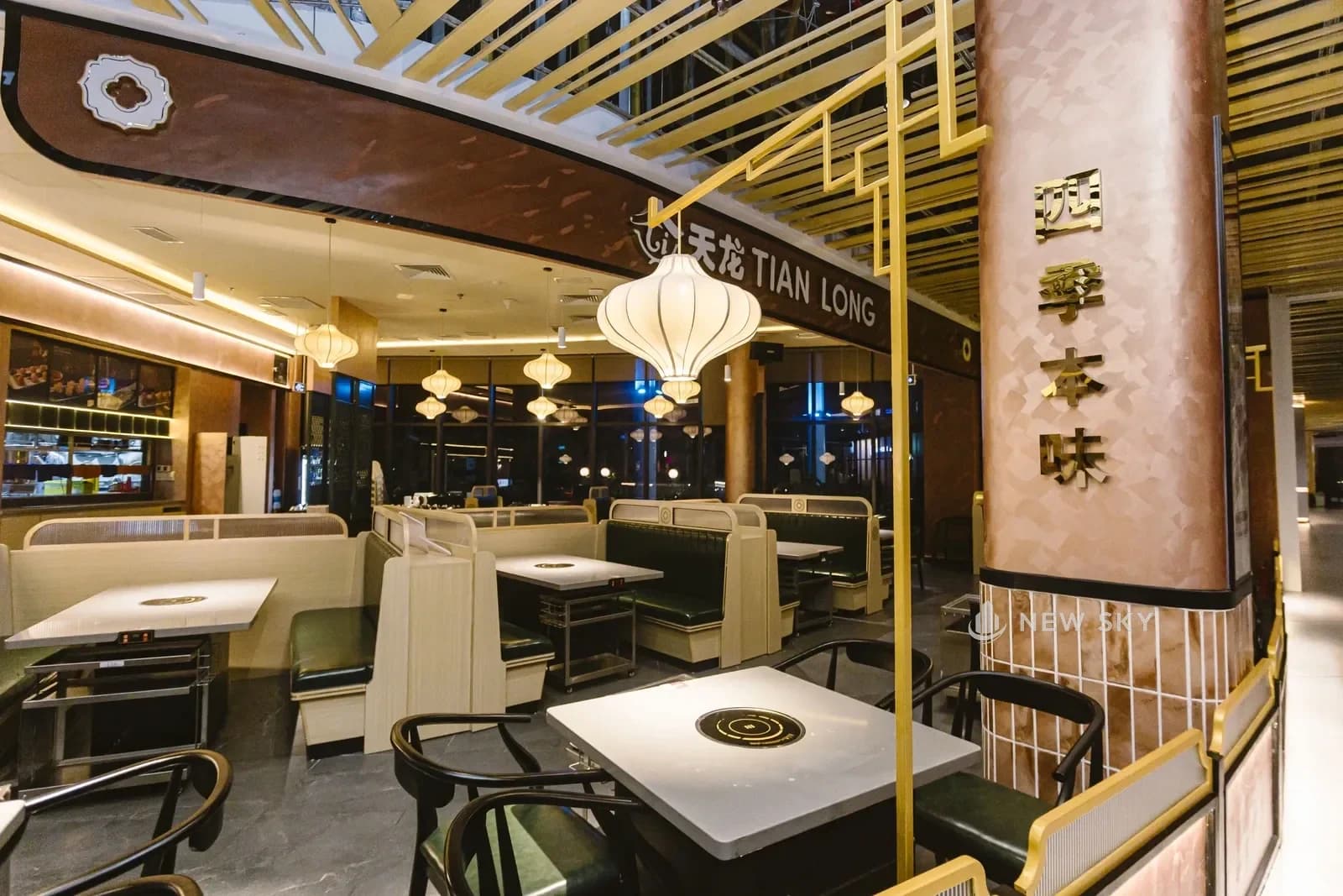 Mặt tiền Tian Long Aeon Mall Huế nhìn từ hành lang: biển hiệu chữ nổi trên vòm nâu, trần lam gỗ vàng chạy dọc, đèn lồng vải thả thành hàng phía trong.