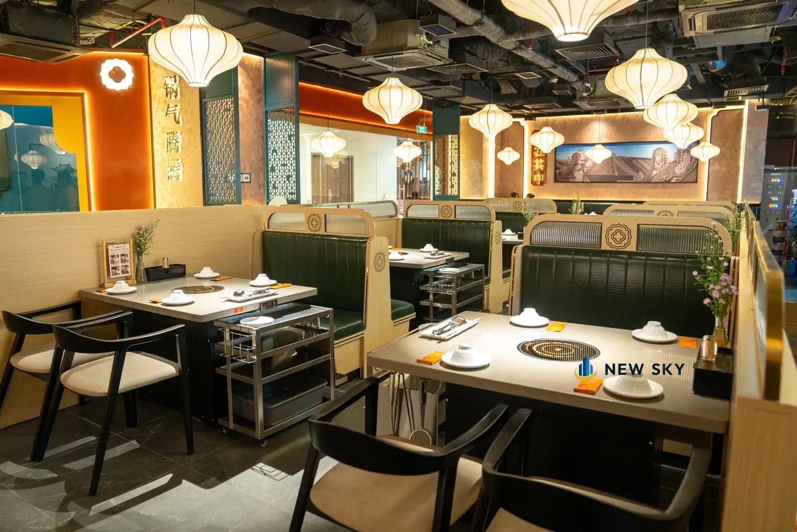 Nhìn dọc lối đi giữa của Tian Long Vincom Center Đồng Khởi: hai hàng khoang ngồi bọc da xanh rêu, đèn lồng vải rủ suốt trần.
