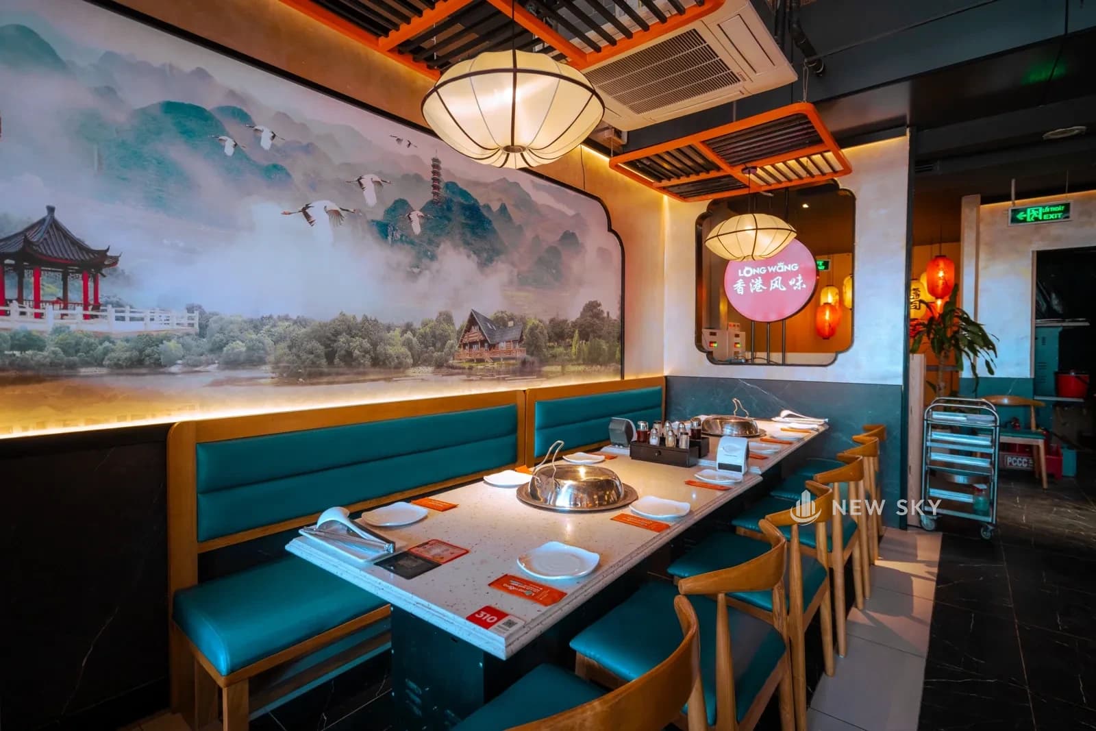 Tranh thuỷ mặc khổ dài trải hết một mảng tường ở Long Wang 409 Minh Khai, phía dưới là dãy bàn lẩu và ghế băng xanh.
