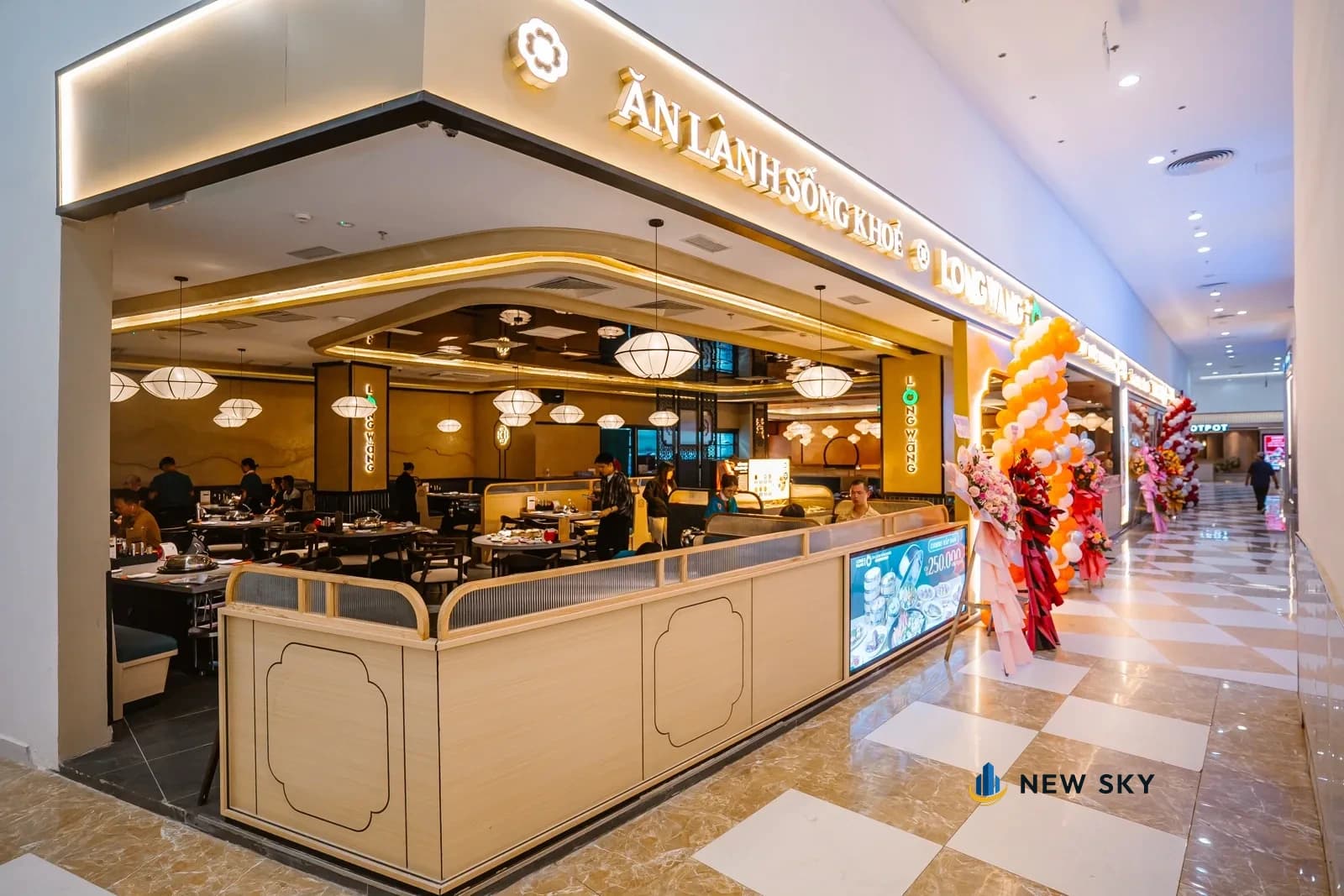 Mặt tiền Long Wang Vincom Plaza 910A Ngô Quyền nhìn từ hành lang trung tâm thương mại: quầy lửng ốp gỗ chạy suốt, biển hiệu chữ nổi trên dầm ngang.