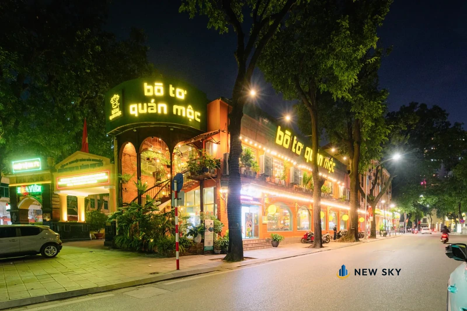 Mặt tiền Bò Tơ Quán Mộc 1 Tăng Bạt Hổ về đêm: biển chữ đèn đặt ở chỗ bo góc nhà, dải biển và đèn dây chạy dọc mặt phố bên cạnh.