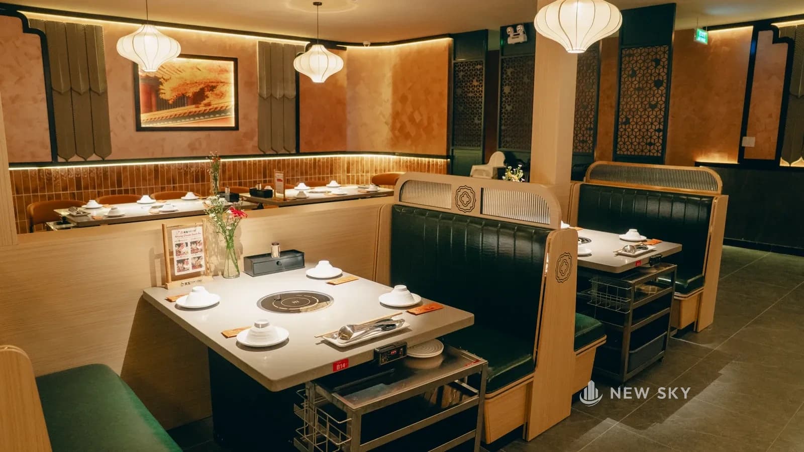 Khoang ngồi ngăn bằng lưng ghế cao, mặt bàn đá khoét bếp lẩu, đèn lồng vải thả ngay trên bàn.