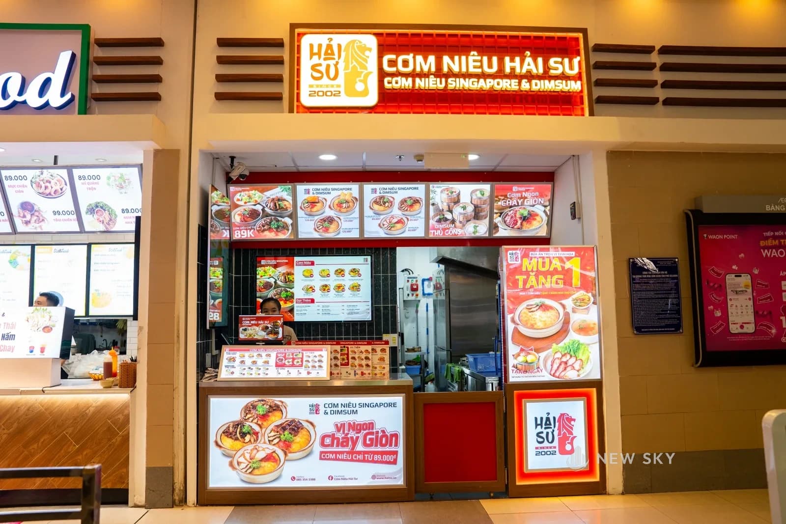 Gian hàng đặt trong dãy quầy của khu ẩm thực tầng hai, bên cạnh là gian khác và bàn ăn chung của trung tâm thương mại.