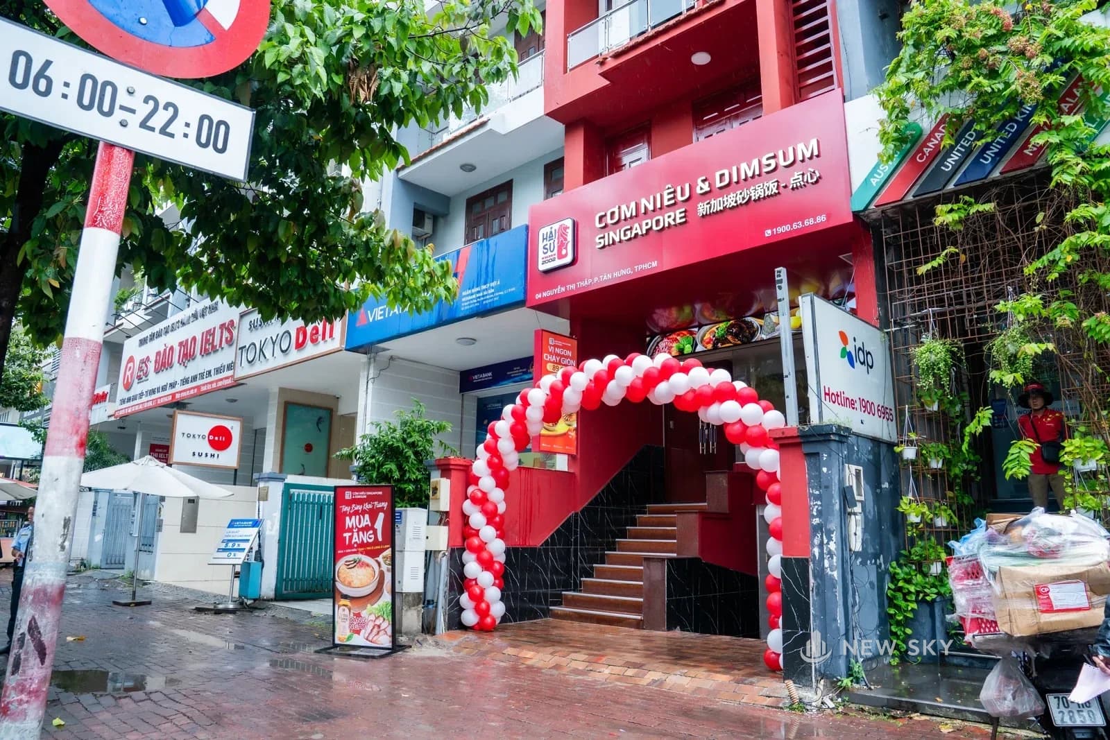 Nhà hàng nhìn từ phía đường Nguyễn Thị Thập, kẹp giữa dãy phố có ngân hàng và trung tâm ngoại ngữ, standee khai trương dựng trước cửa.