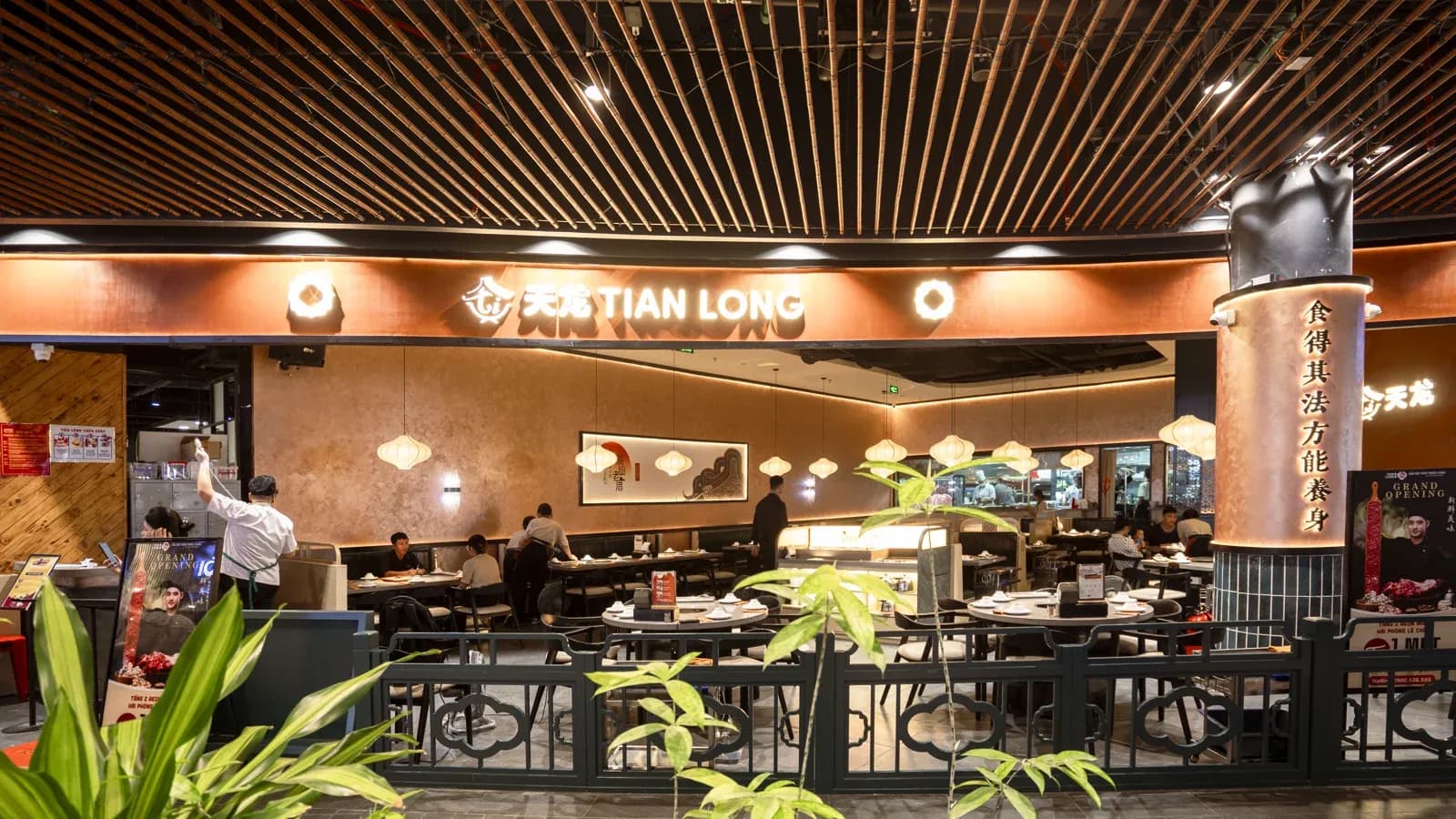 Toàn cảnh gian Tian Long mở ra hành lang Aeon Hải Phòng, lan can thấp hoa văn mây làm ranh, cột ốp đồng khắc chữ Hán.