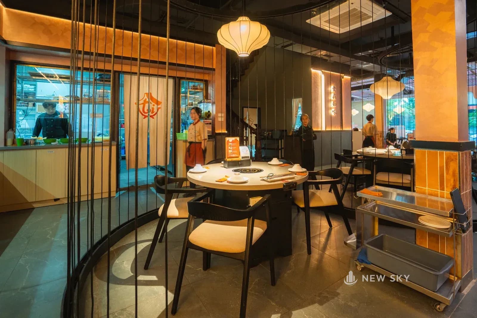 Vòng tròn sợi thép nhìn từ phía khác, phía sau là mặt kính ra đường với cây và người đi lại ngoài vỉa hè.