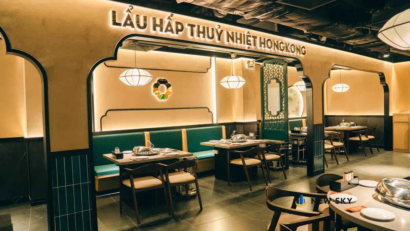 Nhìn dọc bức tường: mỗi vòm nhận đúng một băng ghế, một bàn và một chiếc đèn lồng; phía trên hàng vòm là dải chữ nổi sáng đèn.